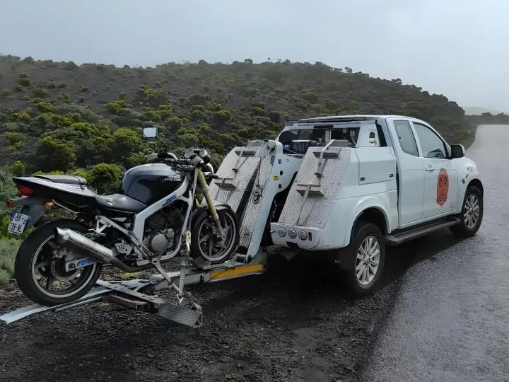 Moto sanglée sur une remorque porte-deux-roues attelée à un véhicule de dépannage