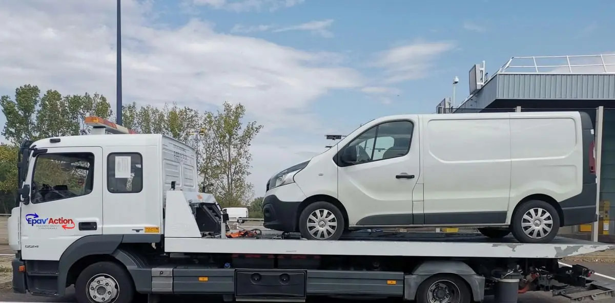 Fourgon utilitaire blanc chargé sur le plateau d'un camion Epav'Action